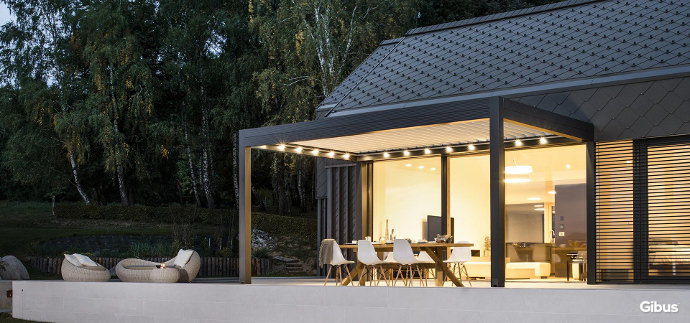 Bioklimatische lamellenpergola vor einem haus, auf einer Terrasse am Abend