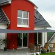 Sonnensegel - elektrisch - in Westfalen in anthrazit vor rot-weißem Haus